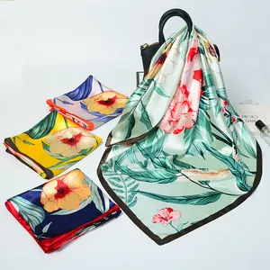 Detail of silk satin scarf showing floral and tropical leaf prints in multiple vibrant colors
