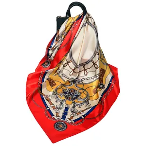 Red square silk scarf with horse chain print draped over a black handbag on white background