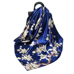 Foulard in seta blu scuro con stampa di magnolia bianca drappeggiato su borsa in pelle