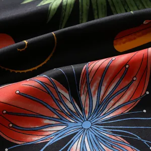 Dettaglio di sciarpa in seta con foglie di palma tropicali e stampa floreale rossa su nero
