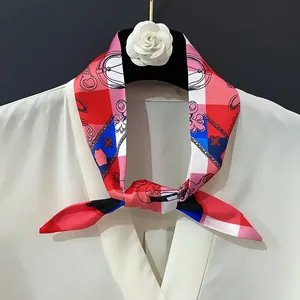 Silk neck scarf with floral chain print worn on white shirt against a dark background