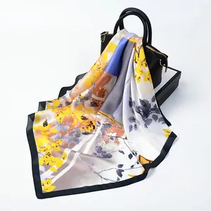 Ivory oil painting silk square scarf with yellow leaf patterns draped on a black bag