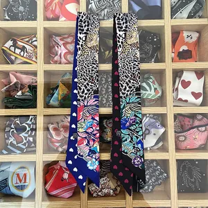 Détail de foulards en soie à motifs léopard et cœurs sur un présentoir en bois