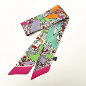 Detail eines bunten Paisley-Twilly-Schals mit 100% Polyester-Waschetikett auf weißem Grund
