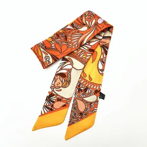 Nahaufnahme des orangefarbenen Seidenschals mit Paisleymuster und Waschetikett