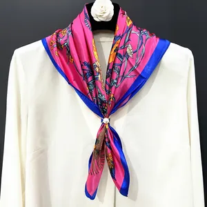 Detail of floral satin scarf in rose pink with a pearl golden buckle on white shirt