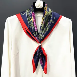 Close-up of silk floral square scarf with a pearl buckle on a white shirt collar