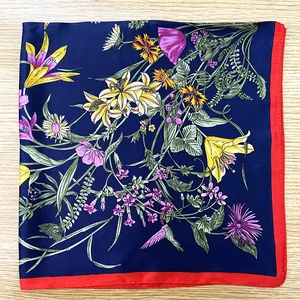 Detailed close-up of dark blue silk scarf with floral and hummingbird patterns on wood