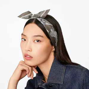 Detailed view of zebra print silk scarf tied as a bow headband on a fashion model