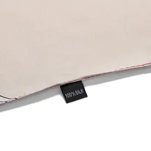 Macro detail of 100% silk scarf with elegant red contrast stitching and fabric label