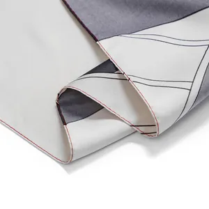 Macro detail of silk scarf with geometric color block patterns and red stitched edges