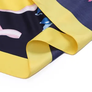 Detail of silk-like scarf featuring pink ribbons and cartoon prints on navy blue fabric