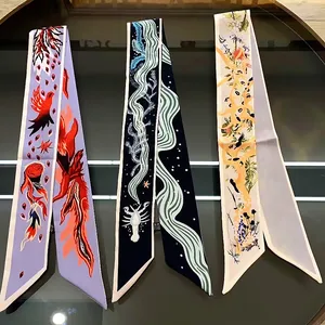 Drei schmale Seidenschals mit Phönix- und Blumenmuster auf einer spiegelnden Oberfläche