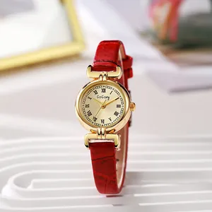 Macro shot of gold watch dial with Roman numerals and red leather strap detail