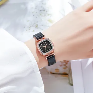 Dettaglio di un piccolo orologio quadrato in oro rosa con cinturino in pelle nera e cristalli