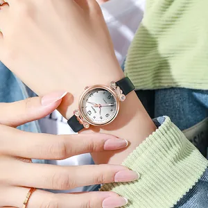 Détail d'une montre en or rose avec attaches en cœur et cristaux sur bracelet en cuir noir