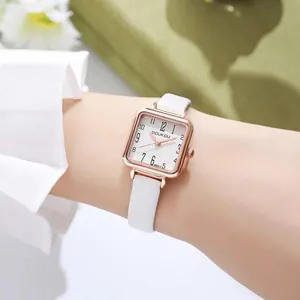 Detail of a square rose gold watch with white leather strap and cross-textured dial