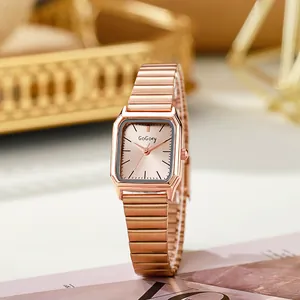 Close-up of rose gold rectangular vintage watch with metallic stretch band on magazine