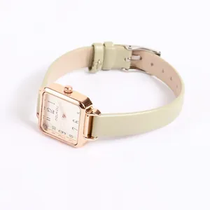 Detail of square rose gold watch with white dial and light green leather strap