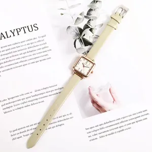 Detail of a square rose gold watch with light green leather strap on a stylish background