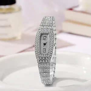 Détail d'une montre tonneau argentée sertie de strass brillants sur plateau blanc