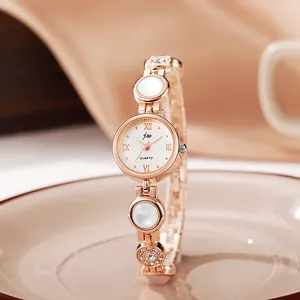Macro detail of rose gold jewelry watch with crystal charms and pearl style band