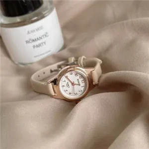Elegant women's quartz watch with cream leather strap and rose gold case on soft fabric