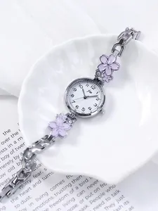 Detail of silver watch band featuring pink cherry blossom charms and sparkling crystals