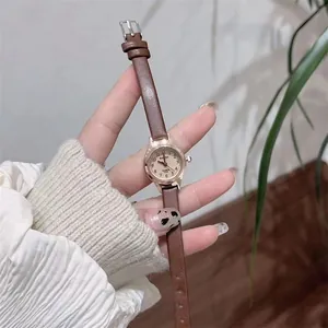 Elegant ladies small round dial quartz watch with brown thin leather strap on wrist