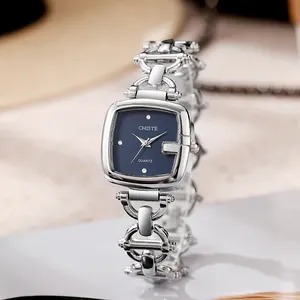 Detail of silver chain watch featuring a square navy dial and sparkling crystal indices