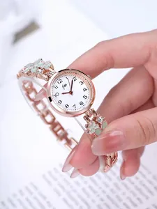 Detailed close-up of rose gold watch bracelet with green enamel flowers and crystals