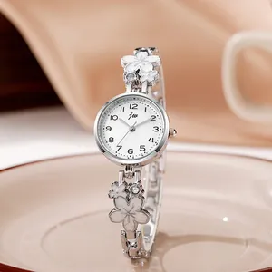 Detail view of a silver floral chain watch with white enamel petals on silk fabric