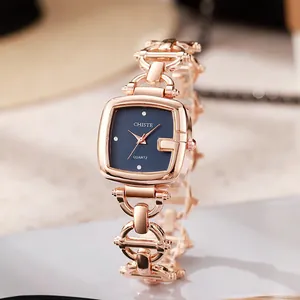 Detail of rose gold square watch with G-shaped bezel and blue dial on jewelry chain