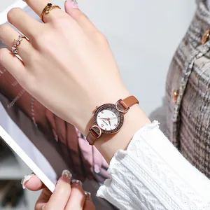 Damen-Quarzuhr mit roségoldener Diamantlünette und braunem Lederarmband am Handgelenk