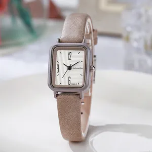 Gros plan d'une montre carrée vintage avec bracelet en cuir marron et cadran beige texturé