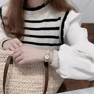 Detail of rose gold quartz watch with beige leather strap and matching metal rings