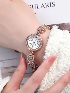 Nahaufnahme einer roségoldenen Quarzuhr mit diamantbesetztem Spiralarmband am Handgelenk