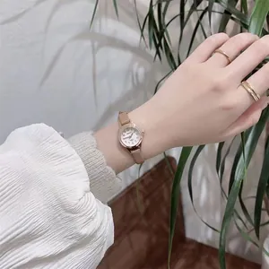 Detail of rose gold small dial women's watch with slim leather strap and numeral markers