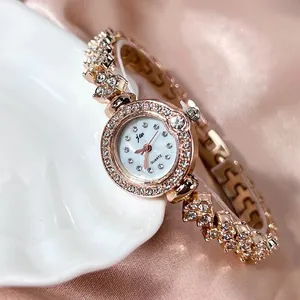 Montre élégante pour femme en or rose avec strass et cadran blanc en nacre raffiné