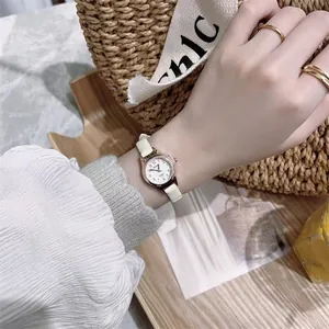 Detail of rose gold quartz watch with white dial and slim cream leather strap
