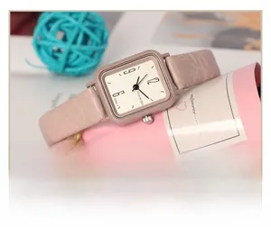 Gros plan d'une montre carrée en or rose avec bracelet en cuir rose et décor