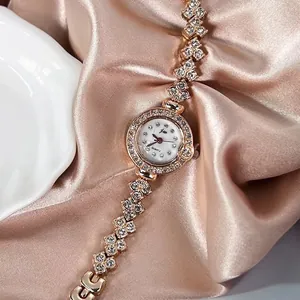 Gros plan d'une montre femme en or rose avec lunette sertie de cristaux et bracelet chaîne