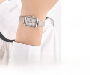 Montre carrée minimaliste avec boîtier argenté mat et bracelet en cuir marron au poignet