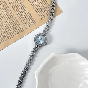 Détail de la montre à maillons argentés avec cadran bleu clair et lunette en cristaux