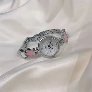 Close-up of silver watch featuring pink star charms on a luxury white satin background