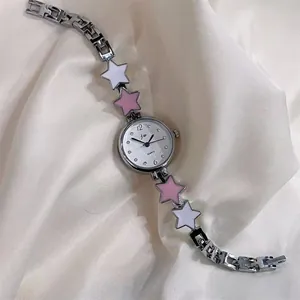 Close-up of women's silver quartz watch with star charms on textured satin fabric