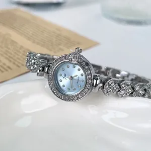 Détail d'une montre bracelet argentée pour femme avec lunette en cristal et strass