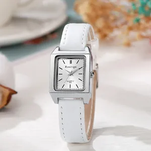Detail view of a square silver watch with a white leather strap and minimalist dial