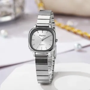 Detail of a square silver quartz watch with a sleek metal link band on a white pedestal