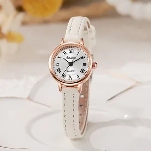 Detalle de esfera de reloj oro rosa con números romanos y correa de cuero blanco